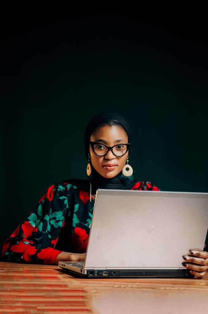 african woman in colorful attire working on laptop